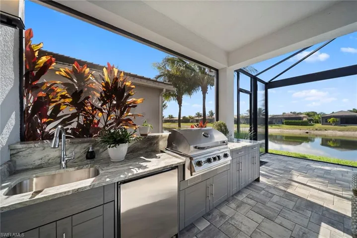 View of patio with an outdoor kitchen, a lanai, a sunroom, and a water view
