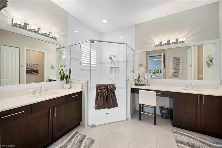 Full bathroom featuring two vanities, a shower stall, light tile patterned flooring, and recessed lighting