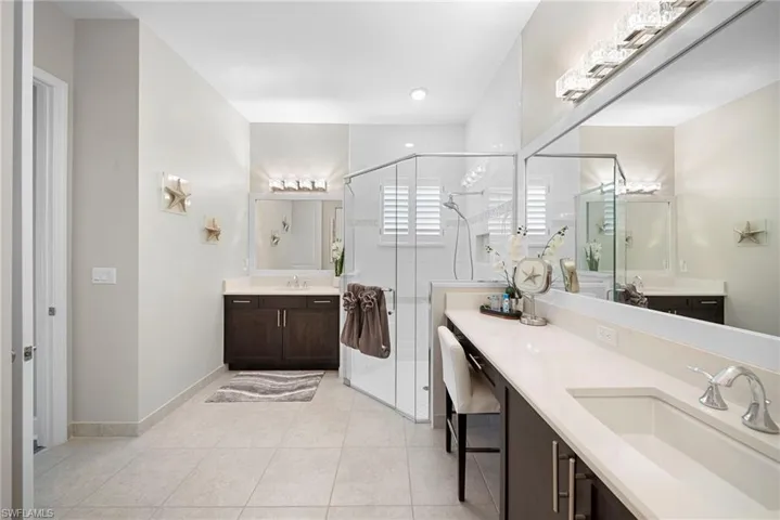 Full bath with a shower stall, two vanities, and light tile patterned floors
