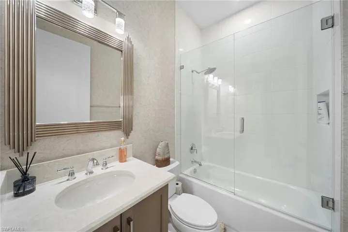 Bathroom featuring bath / shower combo with glass door and vanity