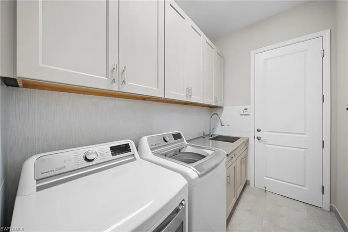 Laundry room with cabinet space, washer and dryer, and light tile patterned flooring