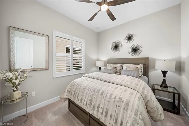 Bedroom with light wood finished floors, ceiling fan, and a tray ceiling