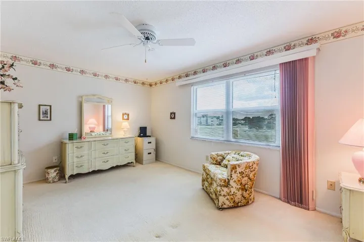 Textured carpet flooring, window with horizontal blinds, wall-mounted ceiling fan, wall-to-wall carpeting