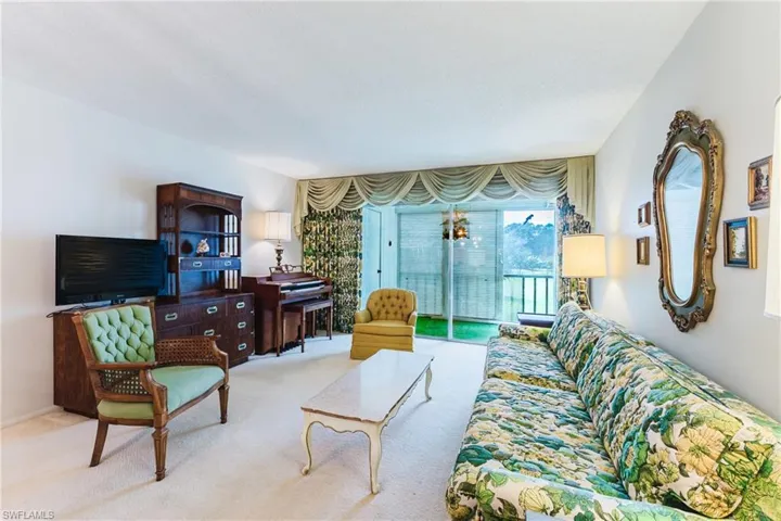 Carpeted living space with white walls and a large sliding glass door