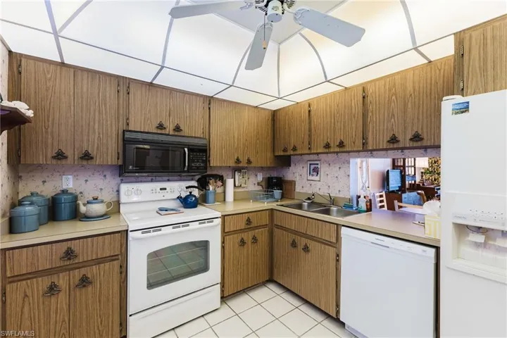 Kitchen featuring wood-finish cabinetry, white appliances, and a ceiling fan