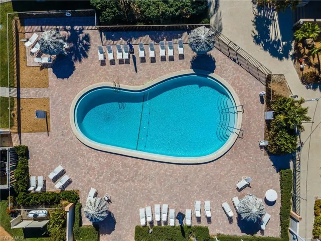 Kidney-shaped swimming pool with integrated steps, surrounded by a paver patio