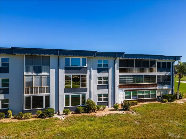 Multi-story building featuring screened balconies, multiple window configurations, and a stucco exterior
