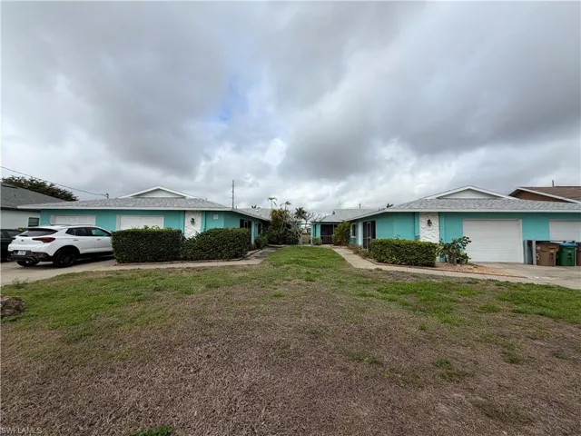 View of front of house featuring an attached garage, a front yard, and driveway
