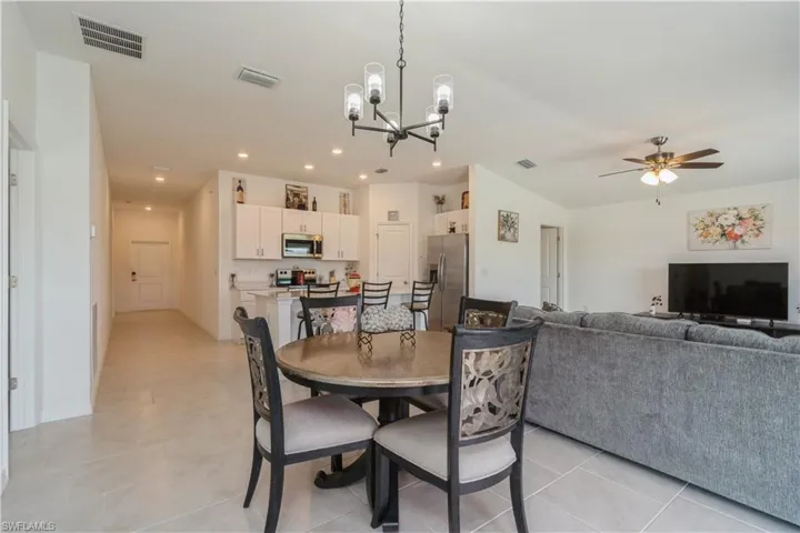 Tiled dining room with ceiling fan with notable chandelier