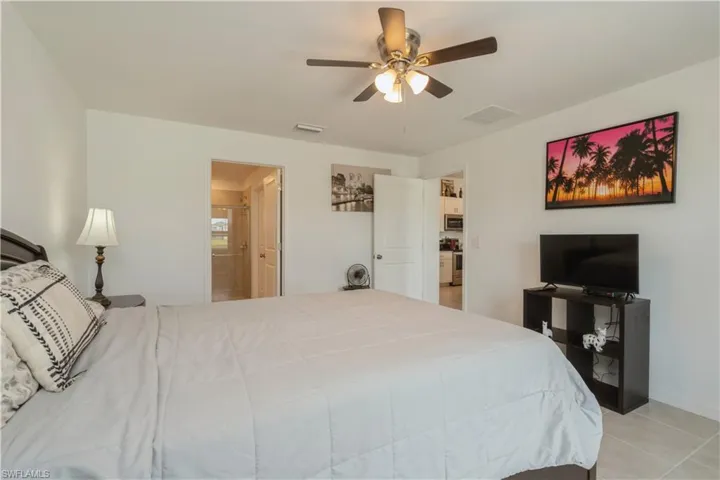 Tiled bedroom featuring ensuite bathroom and ceiling fan