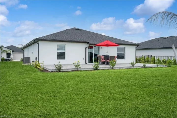 Rear view of house with a patio, central air condition unit, and a lawn