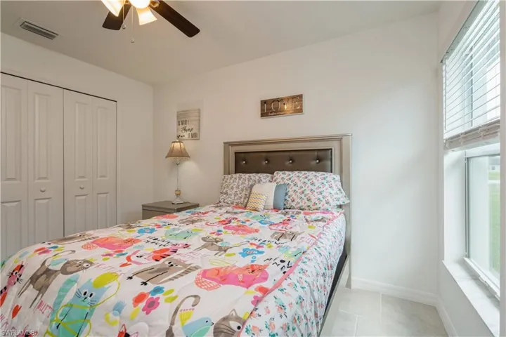 Bedroom with a closet, ceiling fan, tile floors, and multiple windows