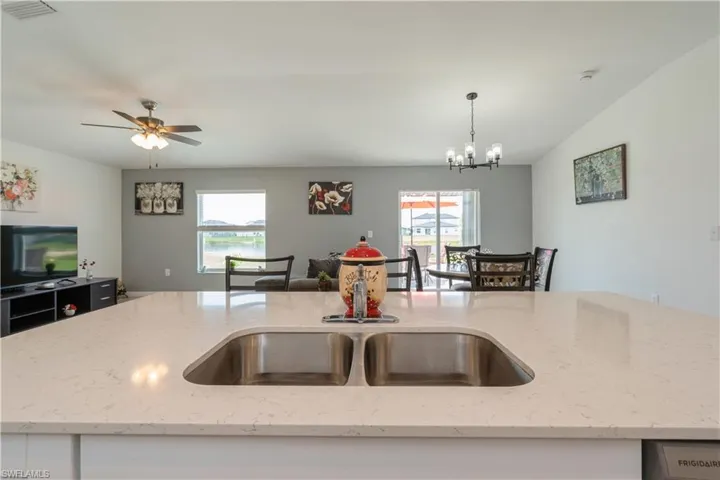 Kitchen featuring decorative light fixtures, light stone counters, and ceiling fan with notable chandelier