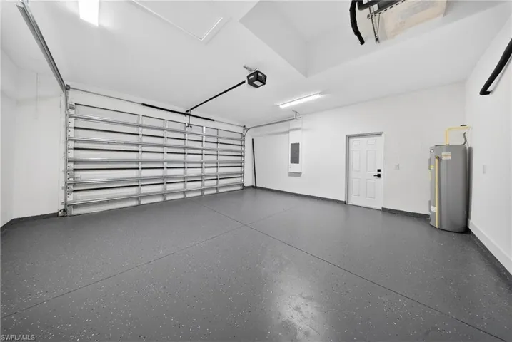 Garage with water heater, electric panel, and a garage door opener
