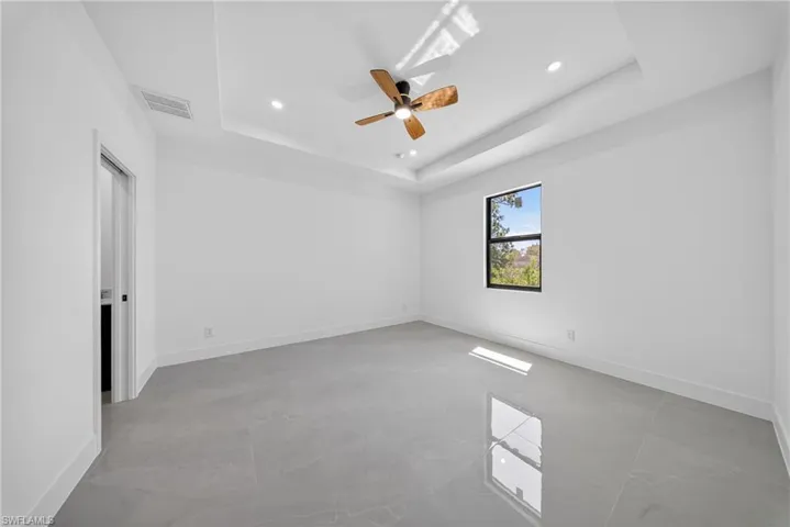Unfurnished room featuring a ceiling fan, recessed lighting, and a tray ceiling