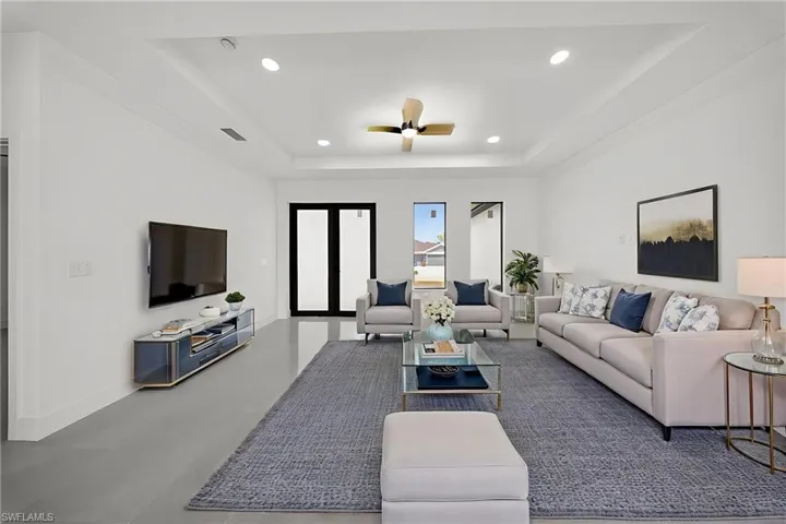 Living area featuring ceiling fan, a tray ceiling, and recessed lighting