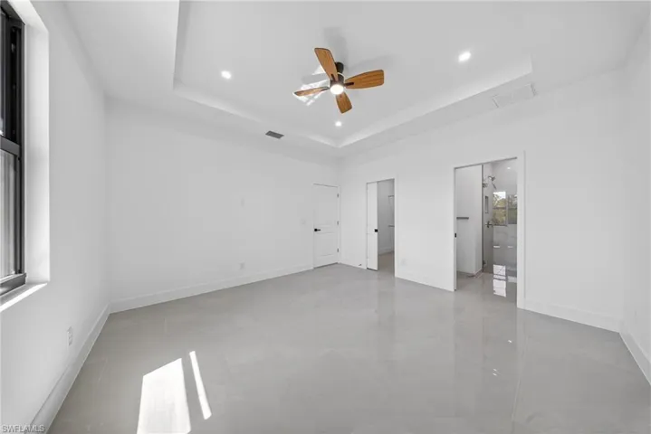 Unfurnished bedroom featuring ceiling fan, a raised ceiling, and recessed lighting