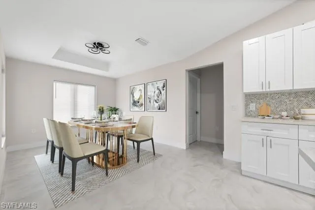 Dining room featuring a tray ceiling and finished concrete flooring