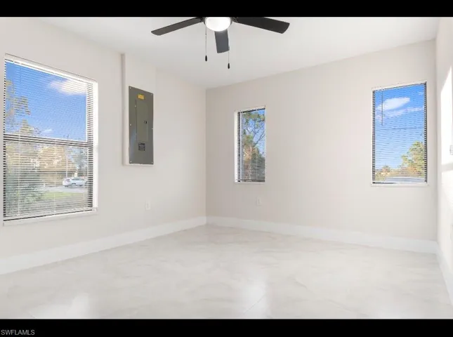 Unfurnished room featuring electric panel and baseboards