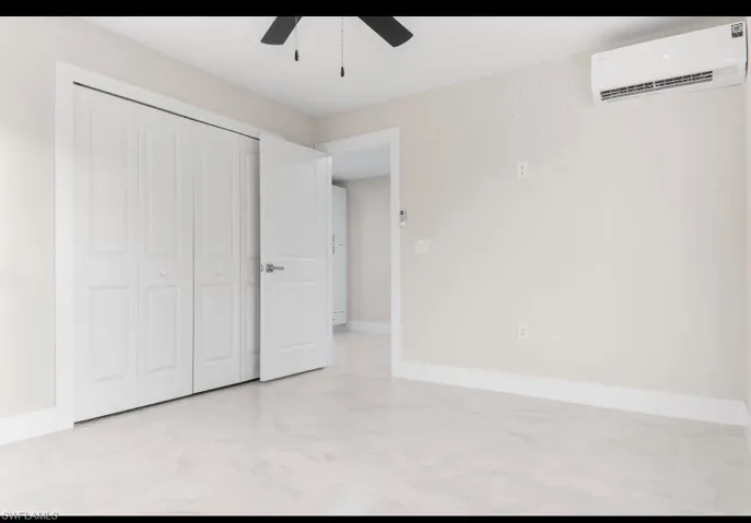 Unfurnished bedroom featuring a wall mounted AC, a ceiling fan, and a closet