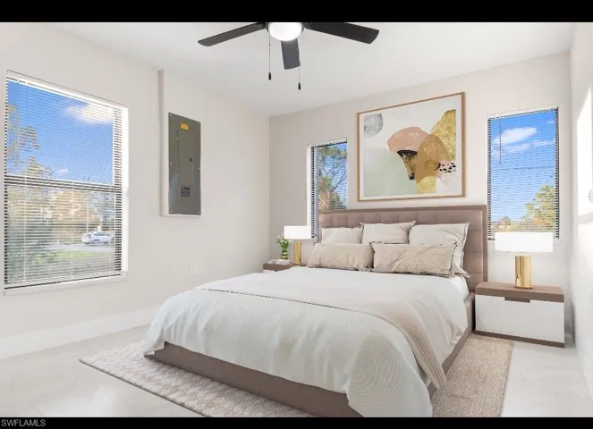Bedroom with electric panel, a ceiling fan, and multiple windows