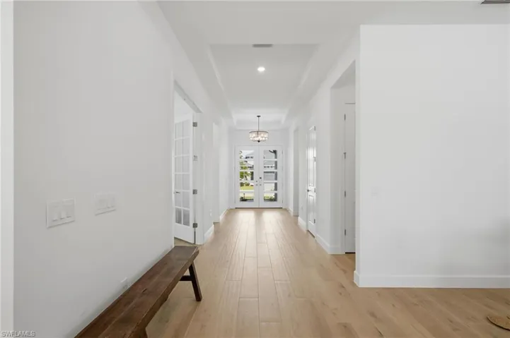 Long hallway with wood-finish flooring, recessed lighting, and a tray ceiling