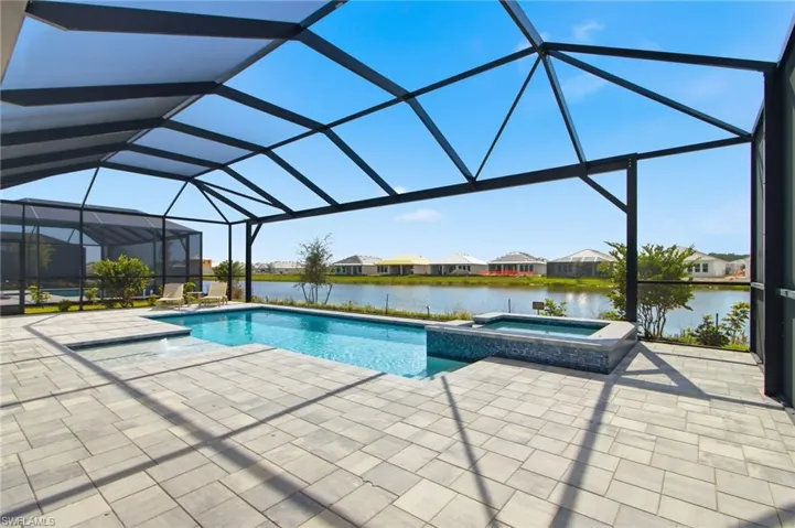 Screened lanai featuring a swimming pool, integrated spa, and paver decking with water frontage