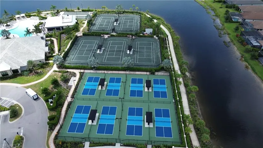 Multiple tennis courts, dedicated pickleball courts, expansive aquatic facility, manicured landscaping, and waterside walking path