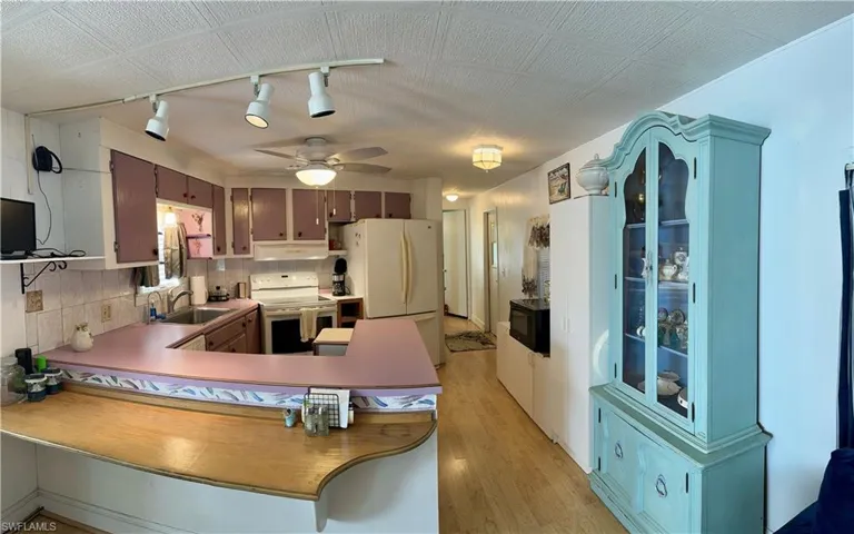 Kitchen featuring, kitchen peninsula, sink, white appliances, and ceiling fan