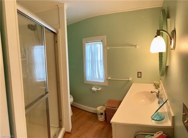 Bathroom with toilet, a shower with shower door, and vanity