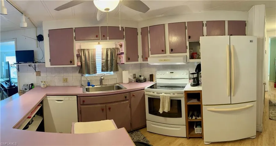 Kitchen with decorative backsplash, sink, white appliances, and ceiling fan