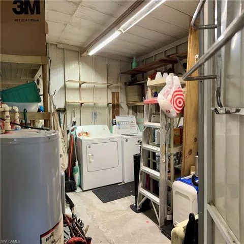 Clothes washing area featuring water heater and washing machine and clothes dryer