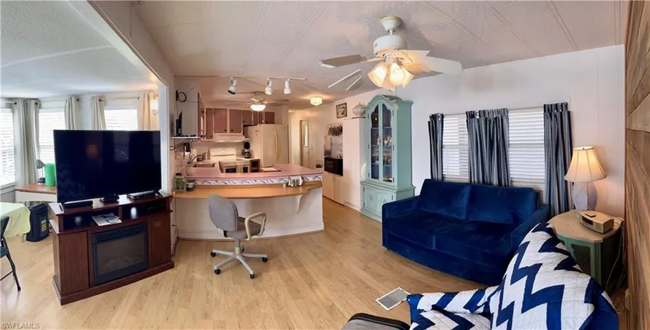Living room featuring wooden walls, track lighting, and ceiling fan