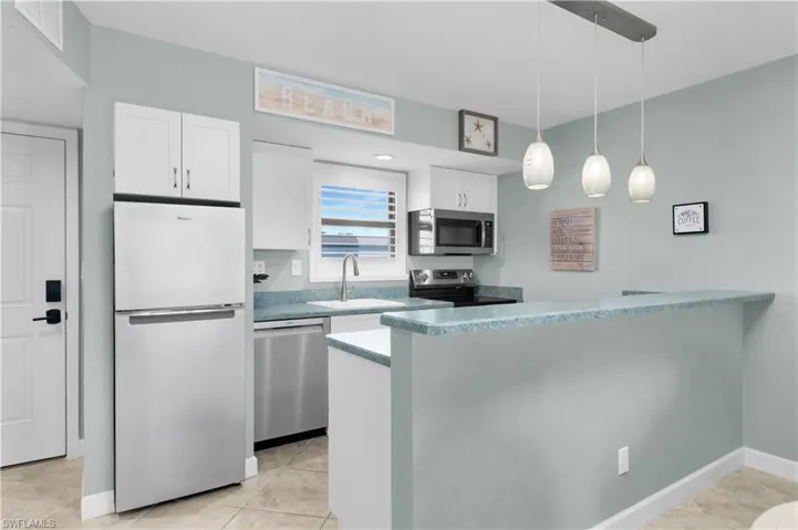Kitchen featuring wide-louvered window shutters, stainless steel appliances, loads of white cabinets & drawers & numerous outlets
