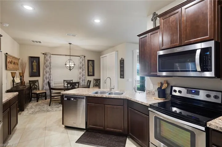 Kitchen featuring appliances with stainless steel finishes, dark brown cabinetry, a peninsula, pendant lighting, and recessed lighting