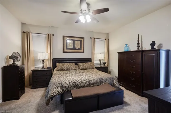 Master bedroom with light carpet and ceiling fan