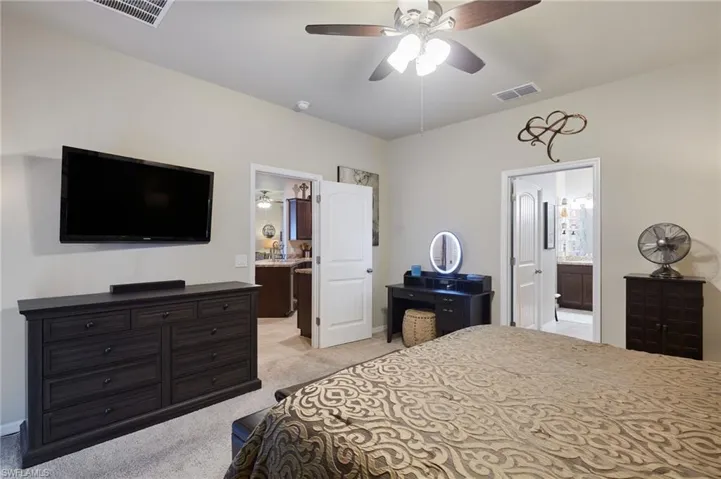 Bedroom featuring connected bathroom, light carpet, and ceiling fan
