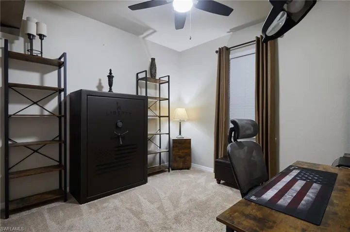 Carpeted bedroom/ home office with a ceiling fan and baseboards