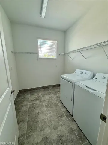 Laundry room featuring tile flooring, white walls, a window with blinds, and built-in wire shelving