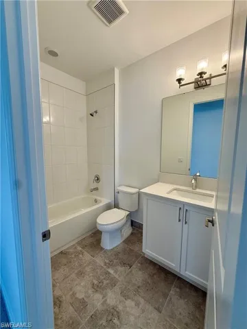 Bathroom featuring a white vanity with integrated sink, a rectangular mirror, and a three-light fixture