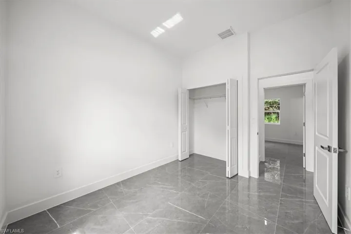 Unfurnished bedroom featuring dark marble finish flooring and a closet