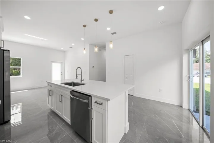 Kitchen with appliances with stainless steel finishes, plenty of natural light, white cabinets, a center island with sink, and recessed lighting