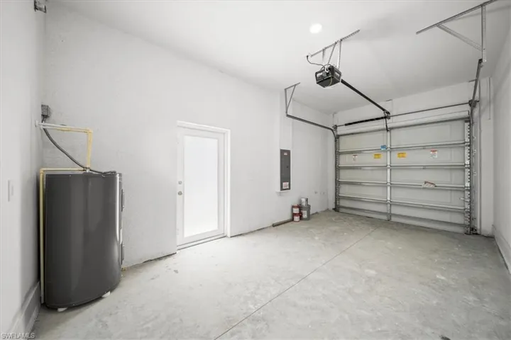 Garage with a garage door opener, water heater, and electric panel