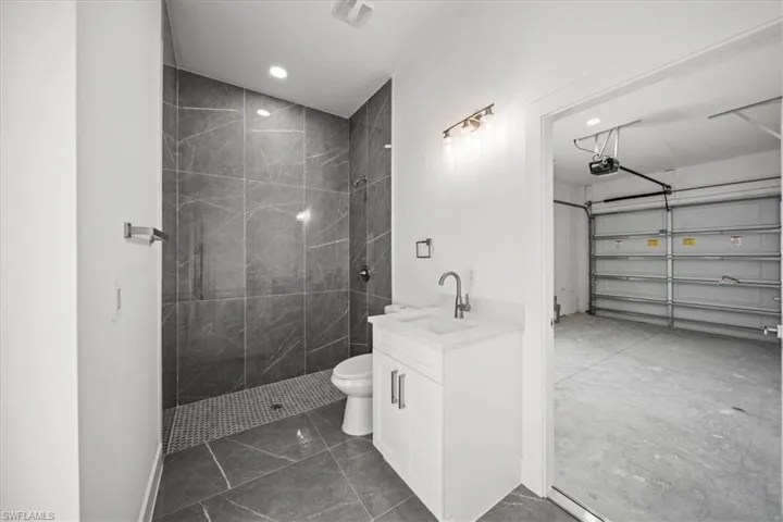 Bathroom with vanity, tiled shower, recessed lighting, and marble finish flooring