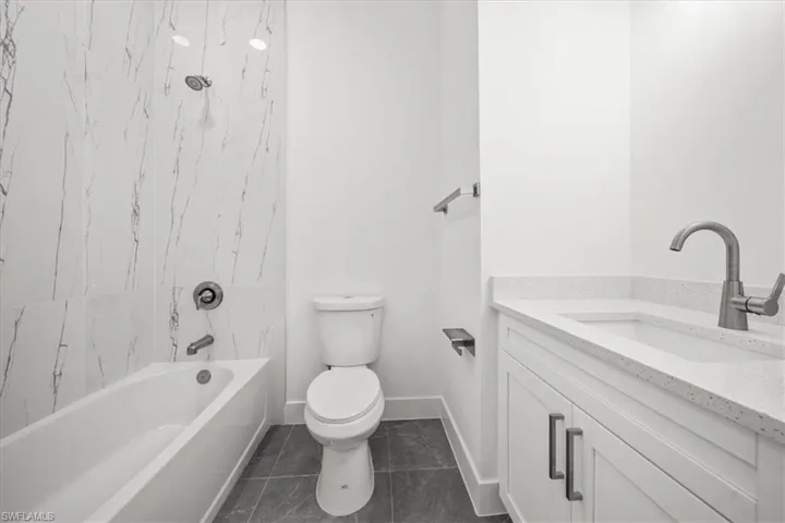 Bathroom featuring vanity, shower / bathtub combination, and tile patterned flooring