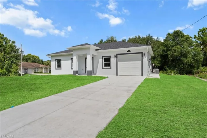 View of front facade featuring driveway, an attached garage, a front lawn, stucco siding, and roof with shingles