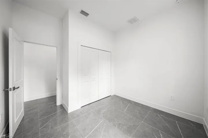 Unfurnished bedroom featuring dark marble finish flooring and a closet