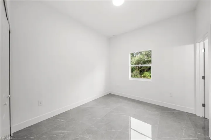 Unfurnished bedroom with marble finish floors and baseboards