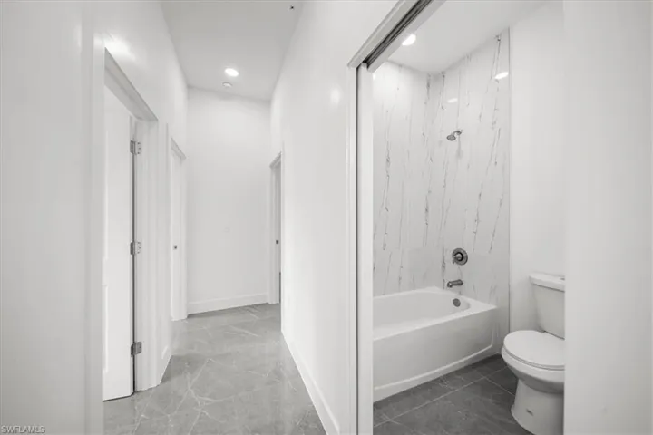 Full bathroom featuring shower / bath combination, marble finish floors, and recessed lighting