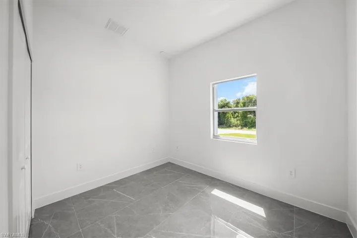 Unfurnished room featuring baseboards and dark marble finish floors
